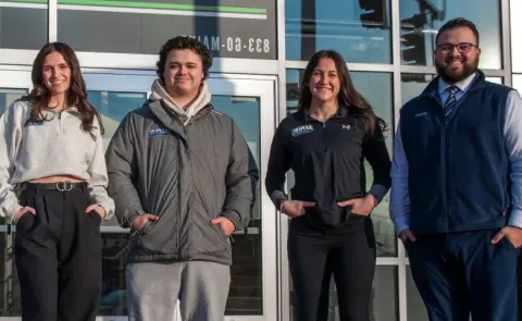 UNE business students pose in front of the Cross Insurance Arena in Portland